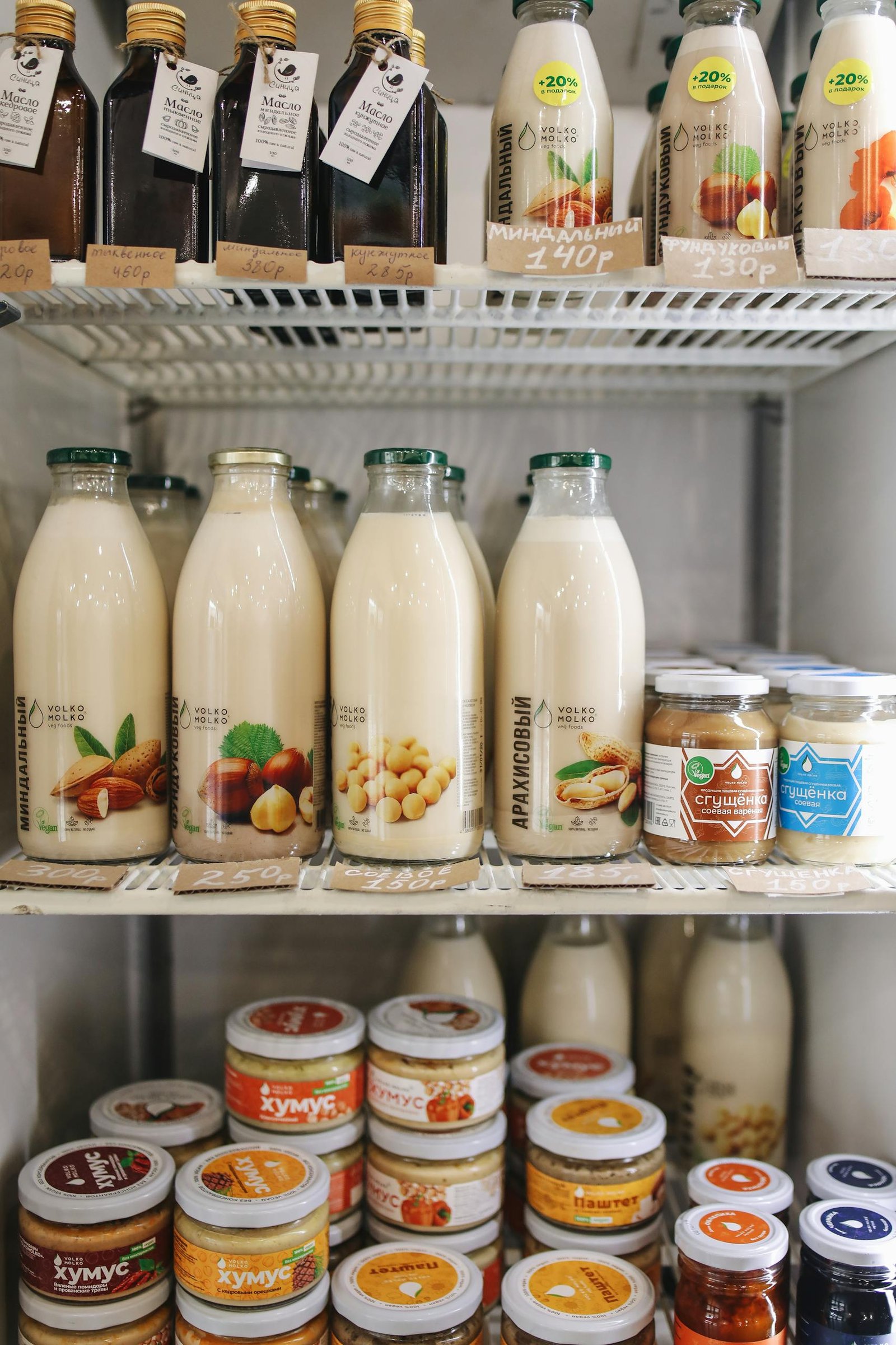 A variety of plant-based milk bottles on display in a refrigerator, showcasing vegan and dairy-free options.