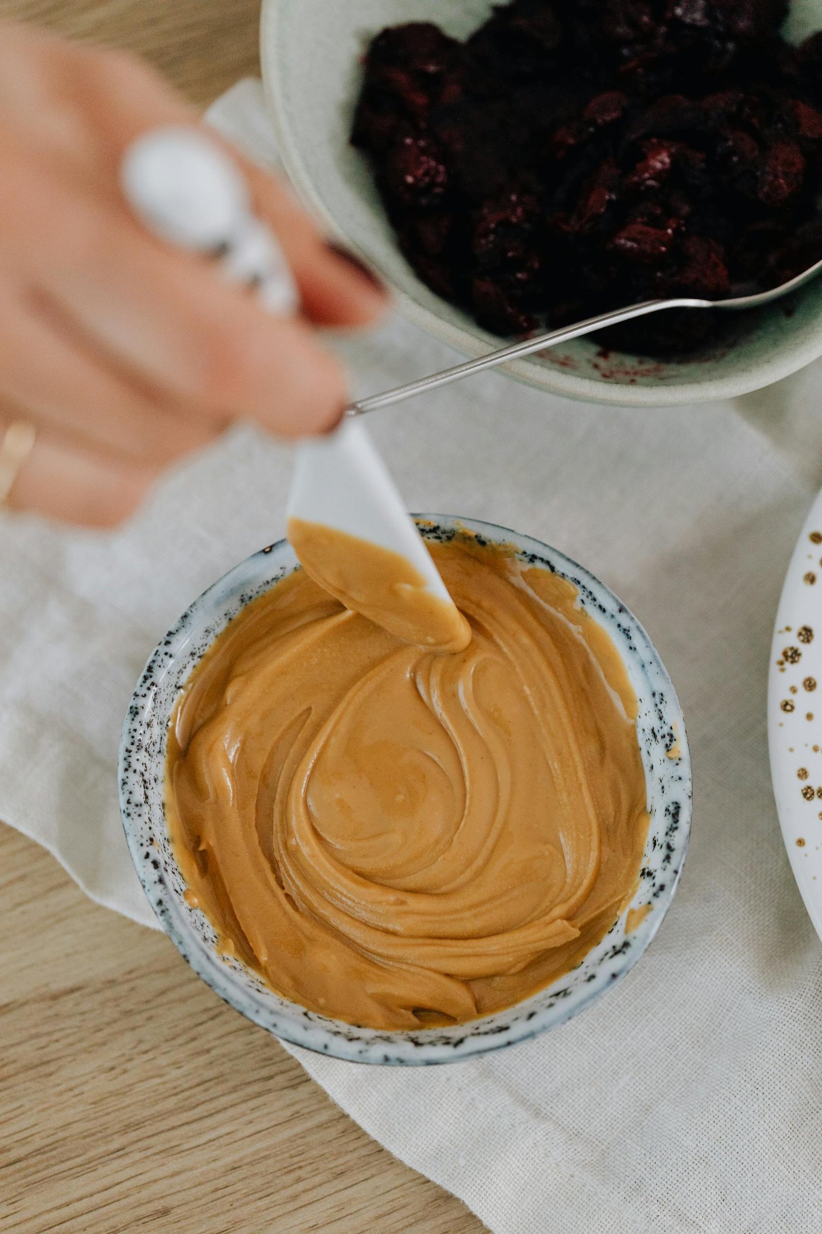Close-up of creamy peanut butter being spread with a knife on a kitchen counter, ideal for food blogs.