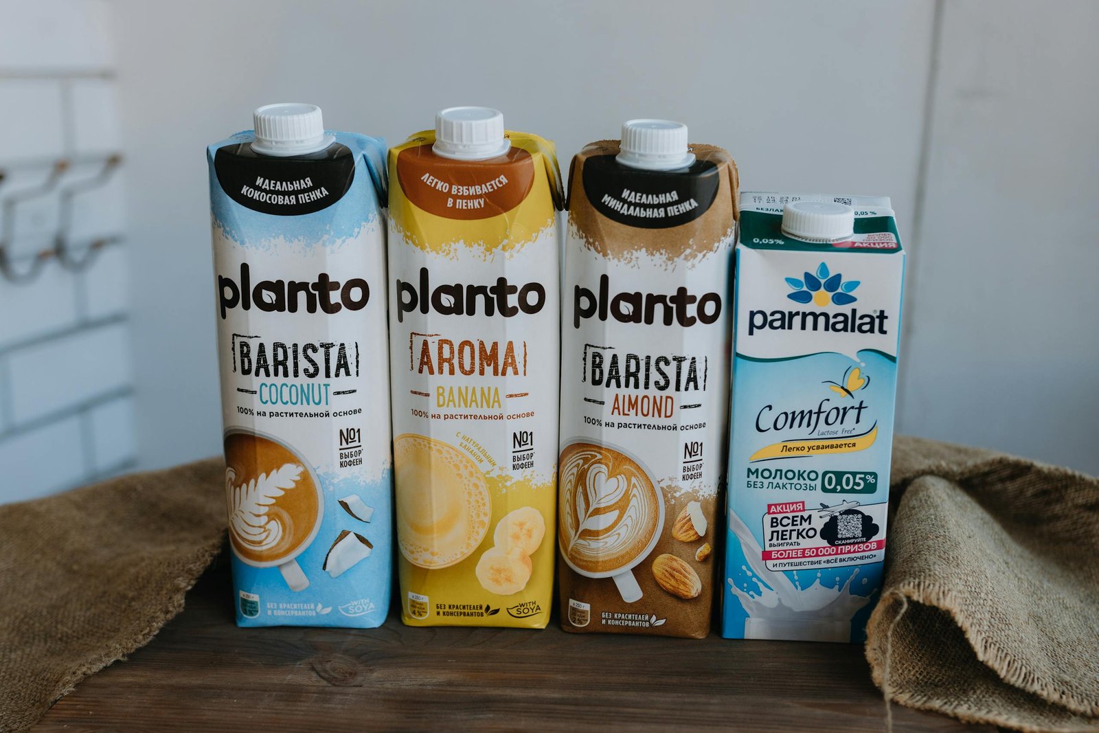 Four plant-based milk cartons including almond, banana, coconut, and lactose-free varieties.